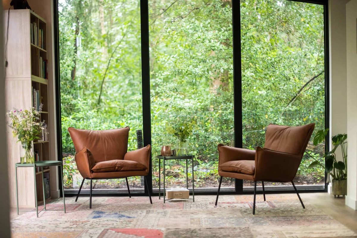 Gespreksruimte met twee comfortabele stoelen en uitzicht op het bos