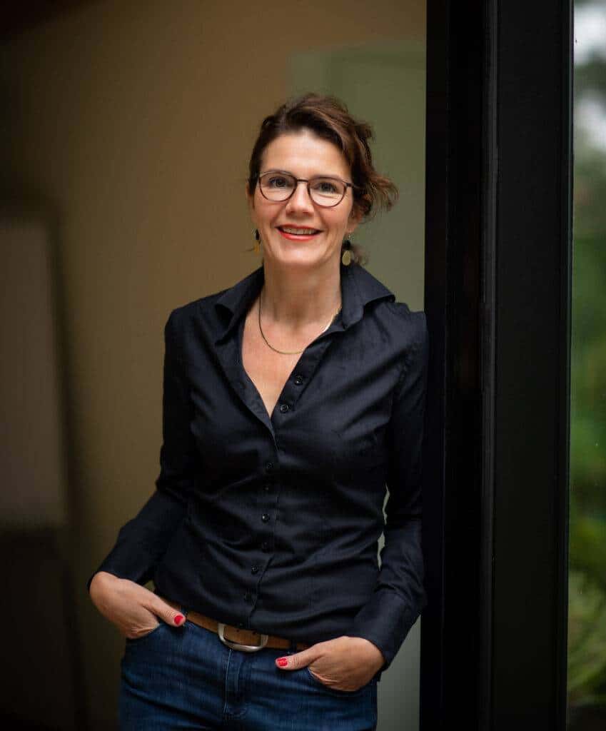 Marlies van Beek glimlachend bij de ingang van haar praktijk in Doorn